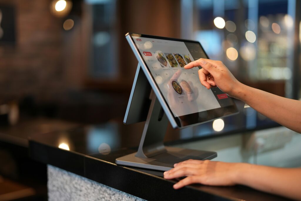 pexels-photo-12935074-12935074 Close-up of a hand interacting with a touchscreen POS system in a restaurant setting.